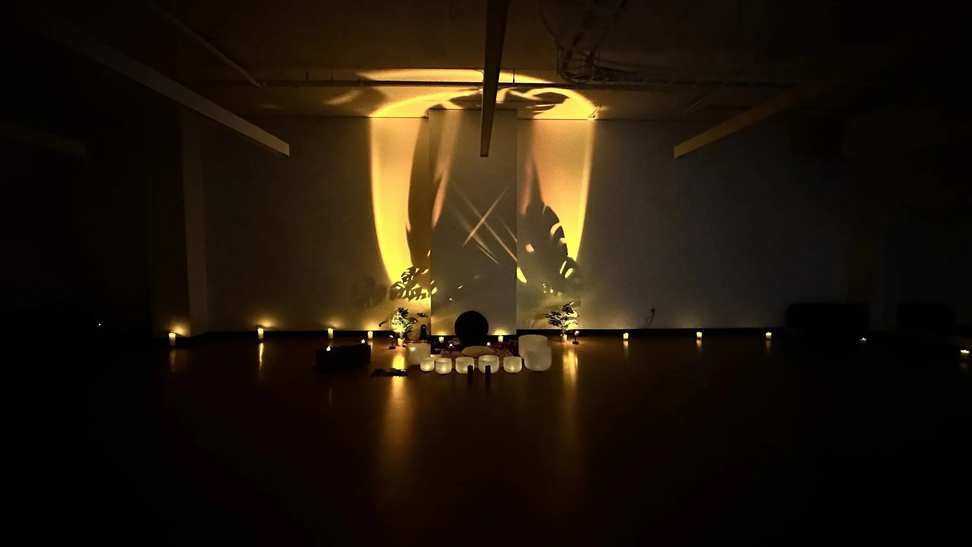 An Aloka session for Lululemon: crystal bowls and candlelight before a wall of leaf shadows